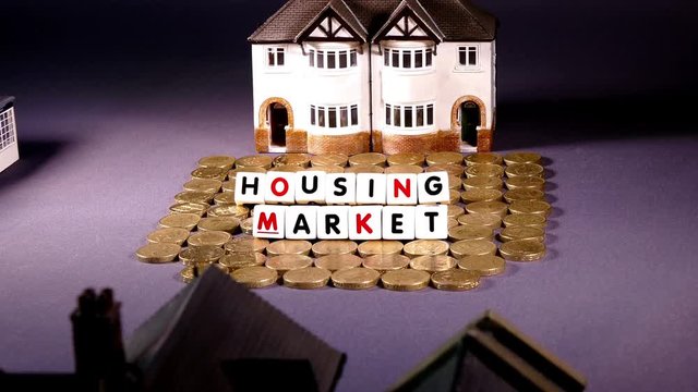 Slide shot of UK housing market concept. Model houses, pound coins and word tiles.