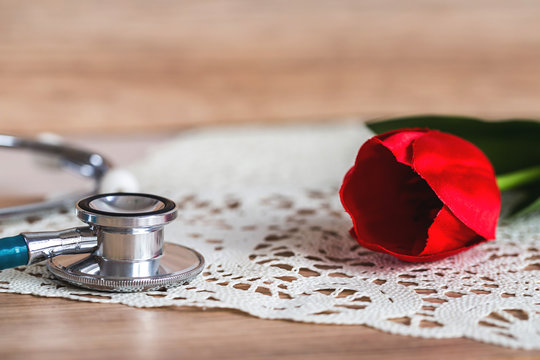 stethoscope on wooden table with red tulip. image for women 