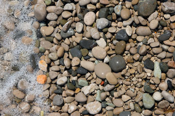 beautiful wet round colored sea pebbles on pebble beach with bub