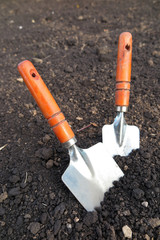 Garden hand trowels in the loosen soil in the garden