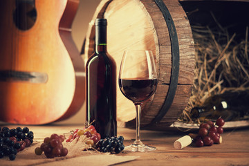 Wine bottle, glass, grapes, barrel and guitar