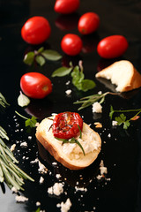 Slice of dried tomato on bread piece on black background