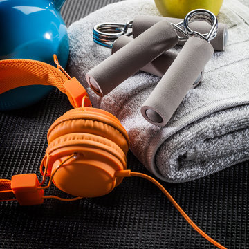 still-life of earphones, hand grip, towel and kettle bell