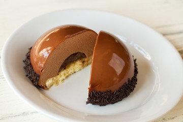 Dessert cut in half. Dough and brown mousse. Small cake with mirror glaze. Delicious chocolate filling.