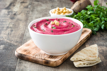Beet hummus and ingredients on wooden table

