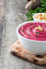 Beet hummus and ingredients on wooden table

