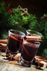 Mulled wine with orange and spices in small glasses on the backg