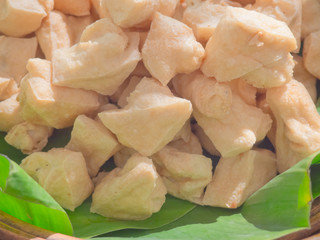 Pile of fried triangle shape tofu on green banana leaf support