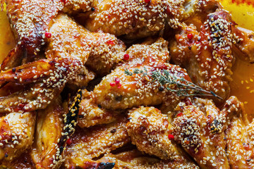 Chicken wings marinated in tomato and honey sauce. Baked with sesame seeds.  Top view.