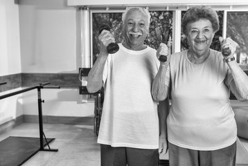 Elder couple making exercises in rehab facility gym