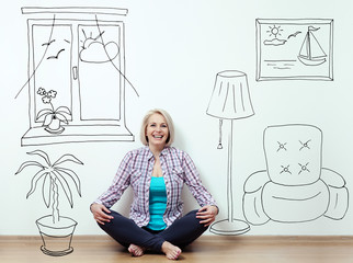 Happy woman sitting on the floor with crossed legs in fashionable clothing on white background in...