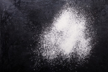Fototapeta na wymiar Flour spilling on black metal background
