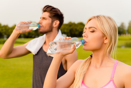 Portrait of tired man and woman drinking water after training