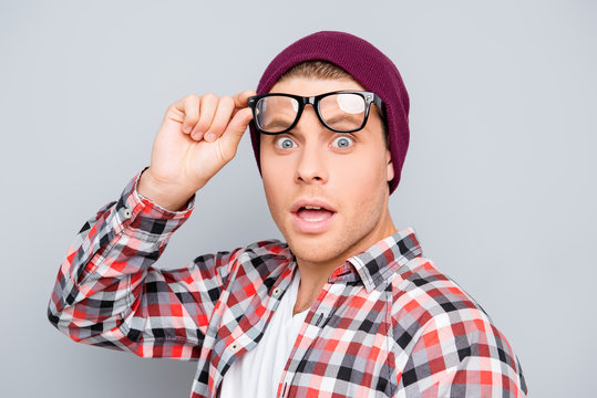 Portrait of shocked young man in hat and glasses with open mouth