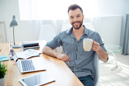 happy young businessman having break and drink coffee at workpla