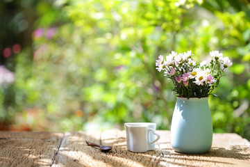 Flowers with vintage pot and heart shaped cup on wooden table