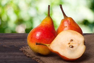 two whole and half of pear on a wooden table with cloth burlap