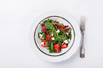 Salad of fresh strawberries,arugula,lettuce,cheese and sesame seeds .healthily cooking concept.selective focus.