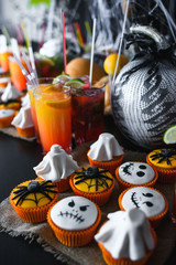 Group of halloween cupcakes with pumpkin and cocktails background