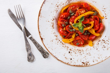 Warm salad with cherry tomatoes,sweet peppers and capers.selective focus.