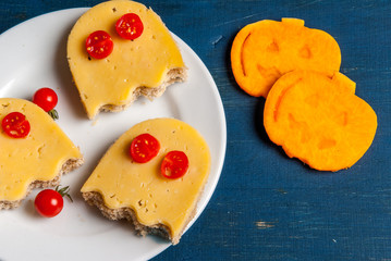 Funny food for a child for Halloween: the sandwiches in the shape of ghosts and slices of fresh pumpkin, carved cookie cutters in the form of a pumpkin