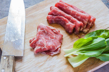 Fresh slices of pork on cutting board and vegetables