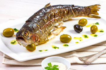 Grilled trout with olive on plate