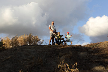 Grandfather with grandsons on hill © Arkady Chubykin