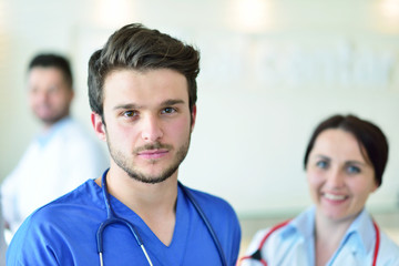 healthcare and medicine concept - attractive male doctor in front of medical group in hospital showing thumbs up