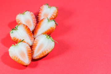 Half of strawberries close up on red paper
