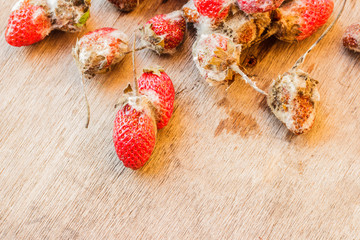 Rotten strawberries on wooden table