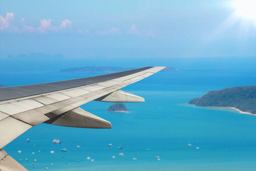 Fototapeta na wymiar Airplane flying over sea blue island - Trave Concept