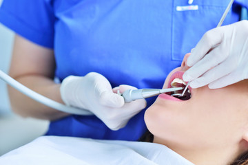 A pretty young woman with a bright, white smile lying in the dentist's chair having a checkup