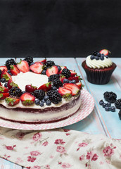 Red velvet cake decorated with berries on a colored background, vertical, selective focus