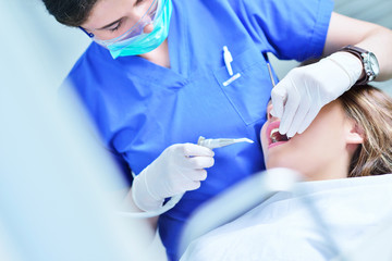 A pretty young woman with a bright, white smile lying in the dentist's chair having a checkup