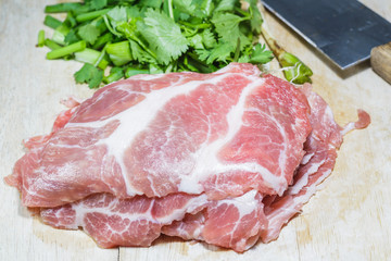 Fresh slices of pork on cutting board and vegetables
