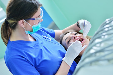 A pretty young woman with a bright, white smile lying in the dentist's chair having a checkup