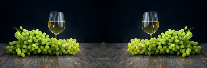 Bunch of grapes on wooden table and glass of white wine. Wide panoramic image.