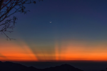 sunset with moon in the mountains