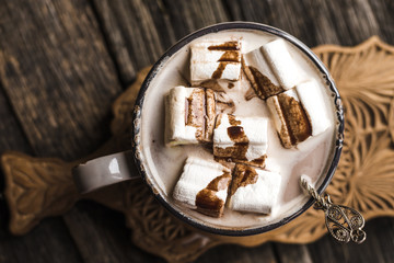 Cup of hot cocoa with marshmallow on cutting board