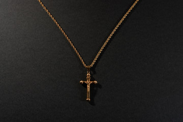 Fototapeta na wymiar gold cross on a chain on a black background