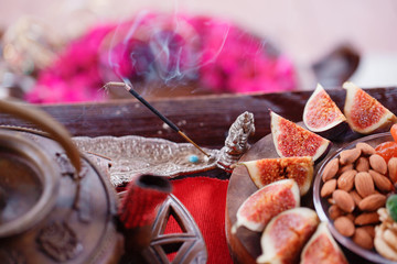 smoking incense. Indian breakfast figs and nuts on a wooden table. Still life with hot steaming green tea