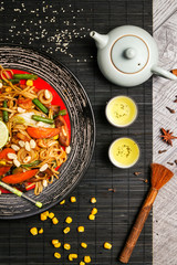 Traditional Japanese food, noodles with roasted chicken with vegetables with chopsticks on a black plate
