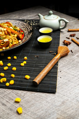 Noodles with grilled chicken and vegetables with chopsticks on a black plate