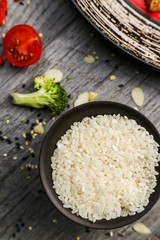White rice in a black plate on a wooden background, cooking process