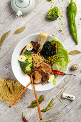 Traditional Japanese cuisine, soup with noodles, vegetables and seafood in a white plate on a wooden background
