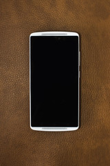White Smart Phone Isolated on leather background. Blank screen