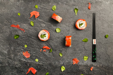 Sushi rolls on a stone background with chopsticks
