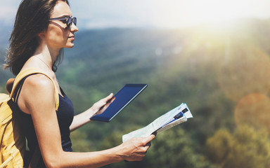 Hipster young girl with backpack enjoying panoramic mountain sea, map and looking at horizon. Tourist traveler texting on tablet computer on background landscape Barcelona view mockup, sun flare
