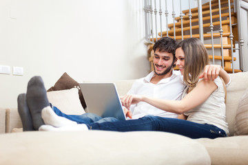 Couple surfing on internet with their laptop in a modern apartment